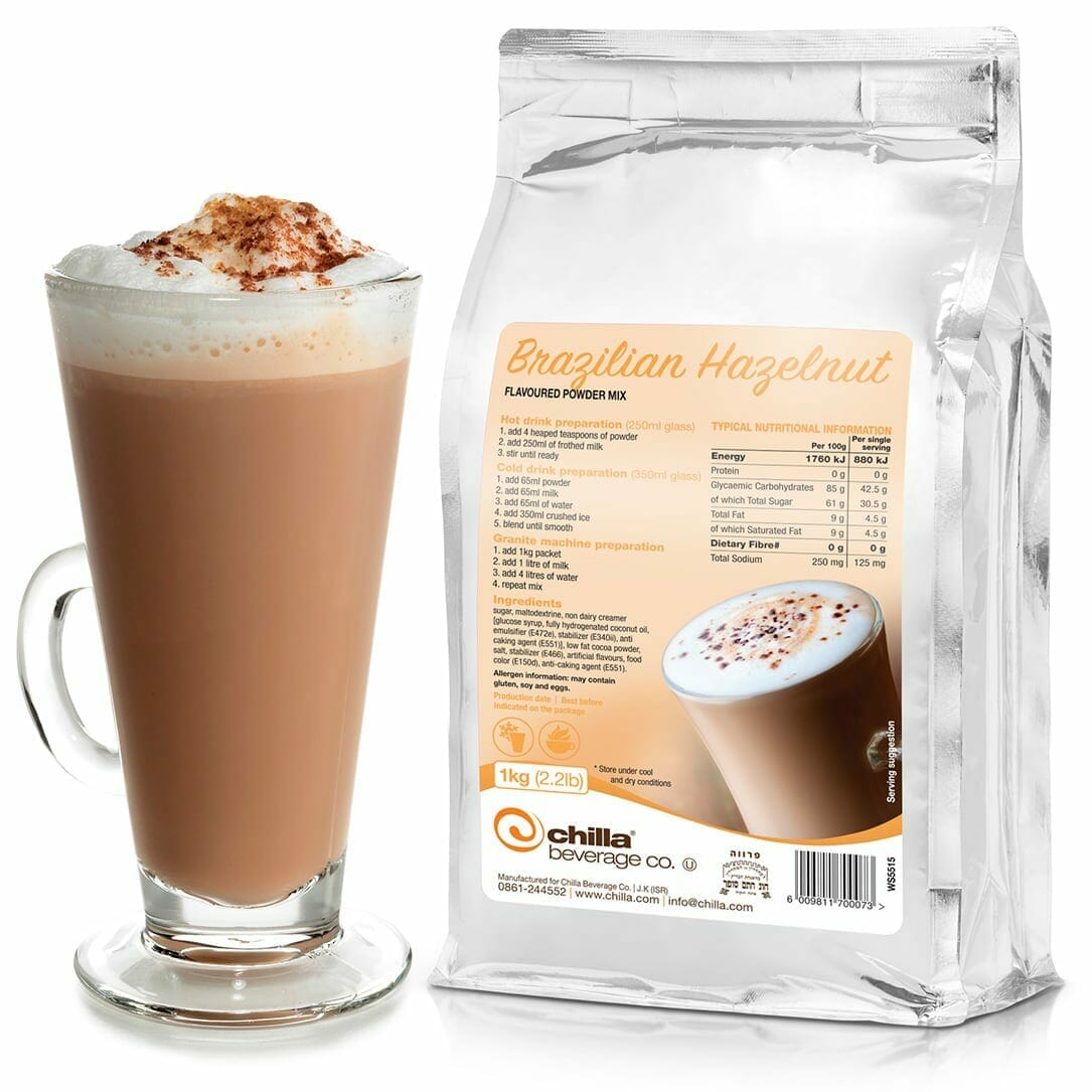 A tall glass of Brazilian hazelnut-flavored coffee topped with frothy milk and cocoa sits next to a silver 1kg package labeled "Chilla Brazilian Hazelnut Powder," which includes preparation instructions and nutritional information.