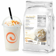 A clear cup is filled with a creamy vanilla shake, topped with whipped cream and caramel drizzle, featuring a black straw. Beside it sits a silver 1kg bag of Chilla Vanilla Powder, showing its nutrition facts, ingredients, and preparation instructions.