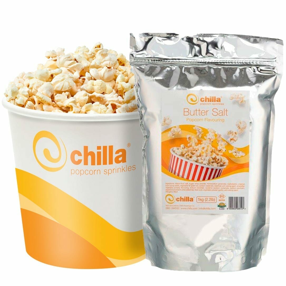 A large tub of fluffy popcorn sits next to a silver bag labeled "Chilla Buttersalt Popcorn Salt 1kg," featuring an image of popcorn in a red-striped bucket. Both items prominently showcase the vibrant orange "Chilla" logo.